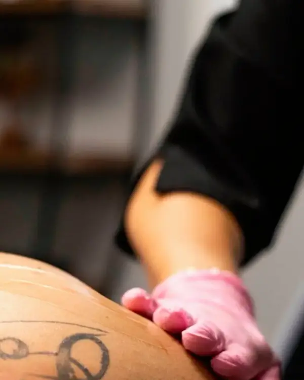 Gant rose d’une technicienne posé sur la peau d’une cliente pendant un soin