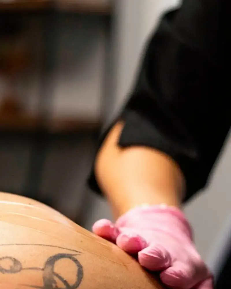 Gant rose d’une technicienne posé sur la peau d’une cliente pendant un soin