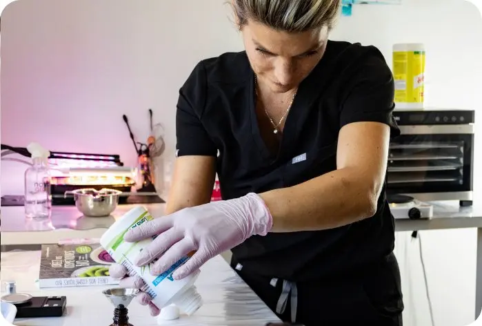 Stéphanie prépare un flacon au comptoir de son salon, vue en plongée